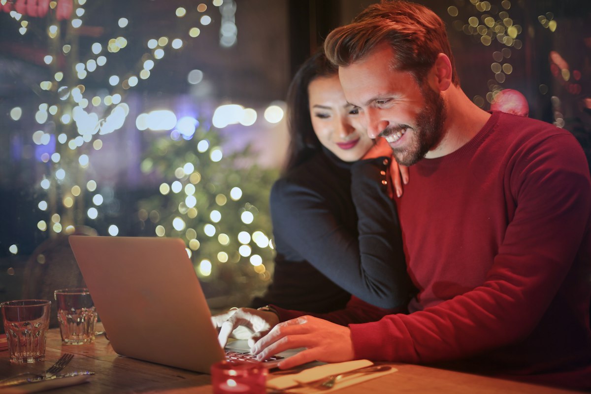 A man and a woman smiling together while looking at a laptop