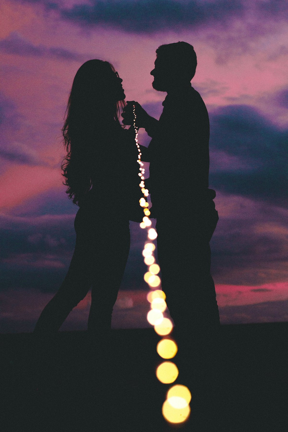 Silhouettes of a man and a woman standing together outdoors in soft evening light
