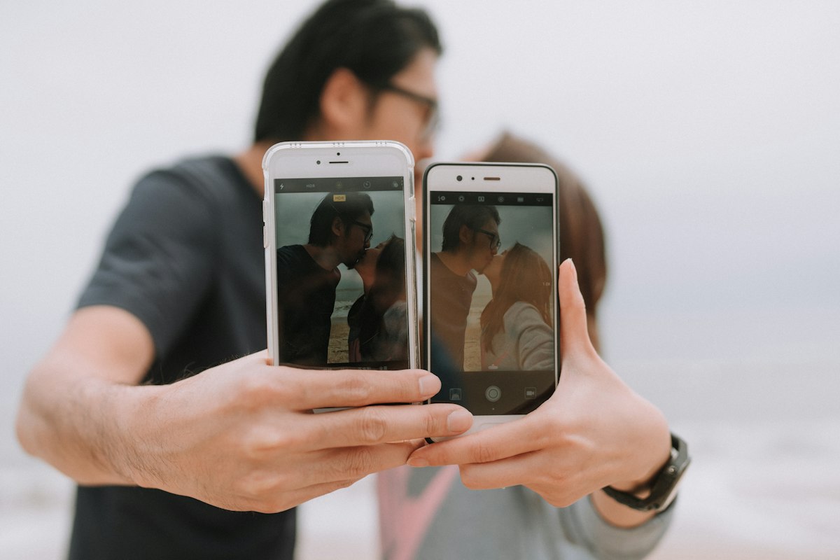 A couple holding up two phones, showing how dating often starts with a screen
